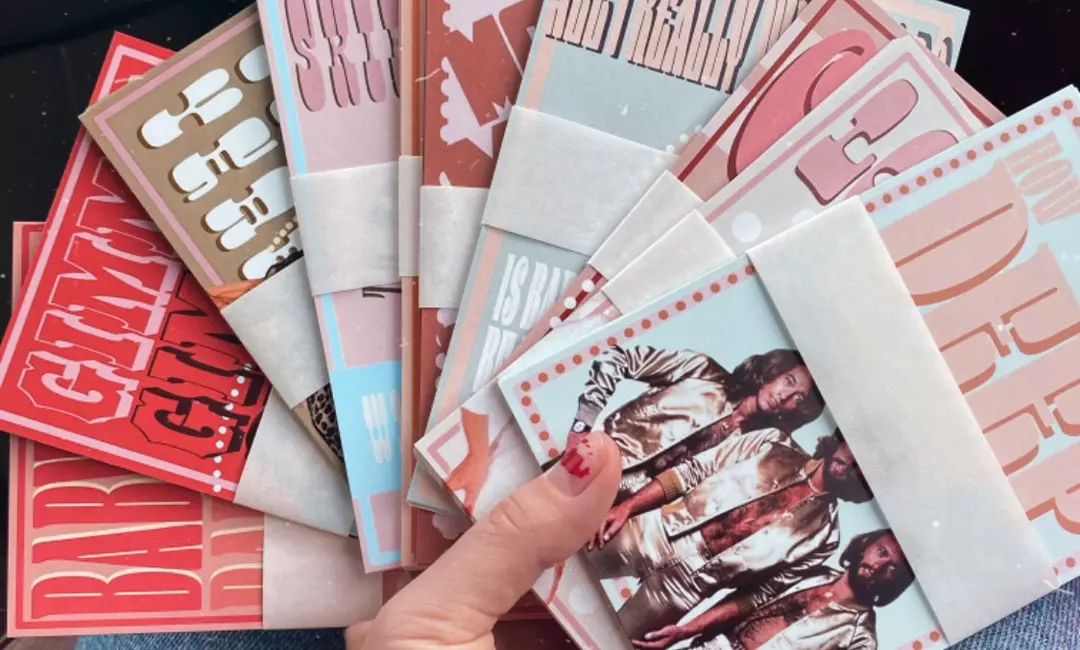Person holding 10 different printed graphic assets