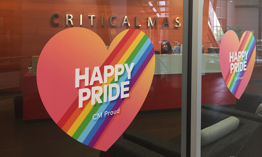 Happy pride rainbow sign on pink heart shaped sticker on glass window